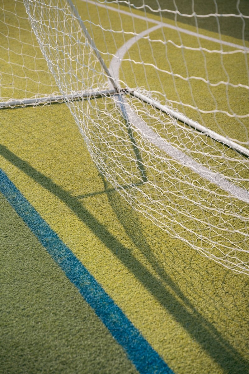 Soccer goal net casts a shadow on the field.